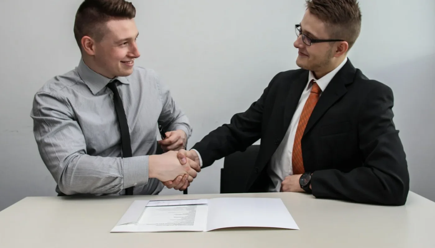 Employer and new hire shaking hands after a sponsored job offer that meets the Skilled Worker visa salary threshold