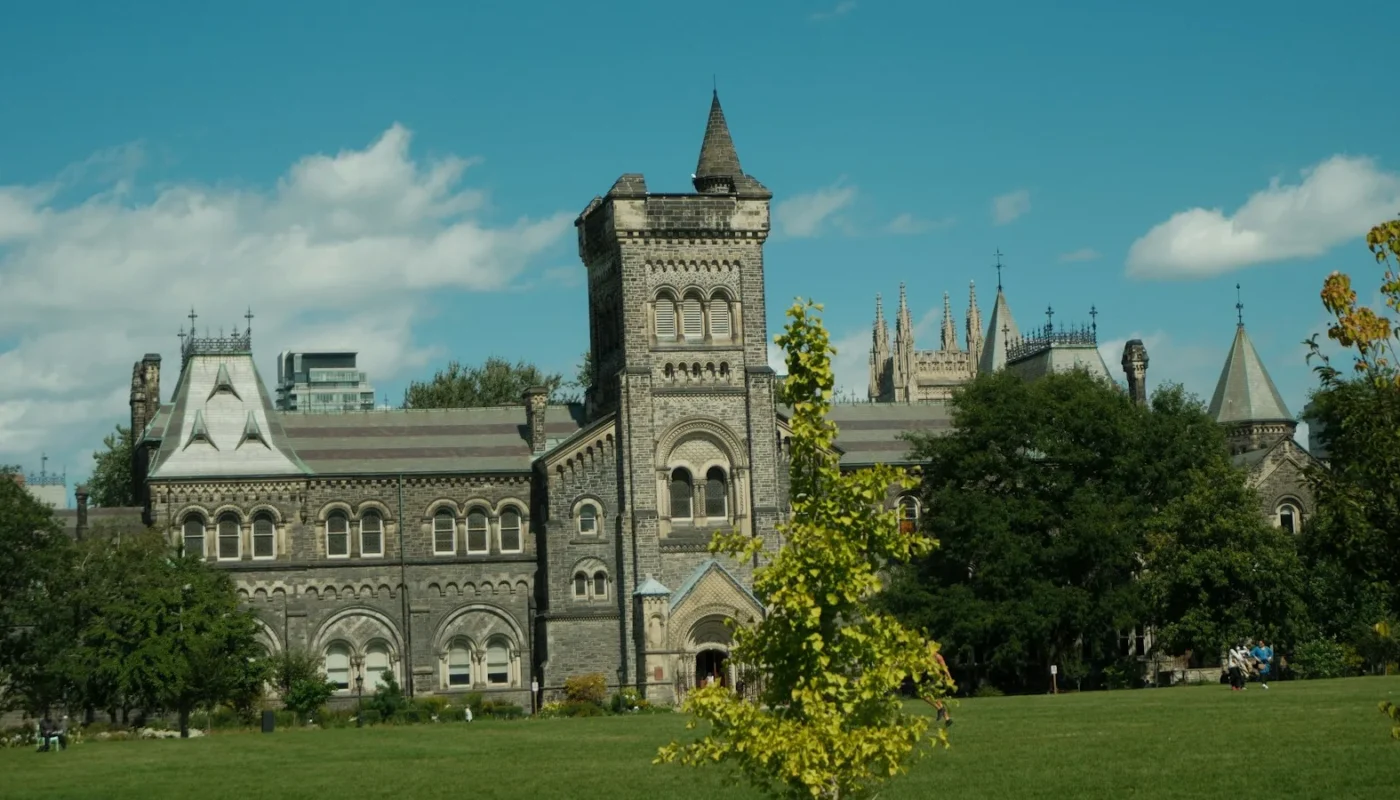 Historic stone university building with a green lawn, illustrating University of Toronto scholarships