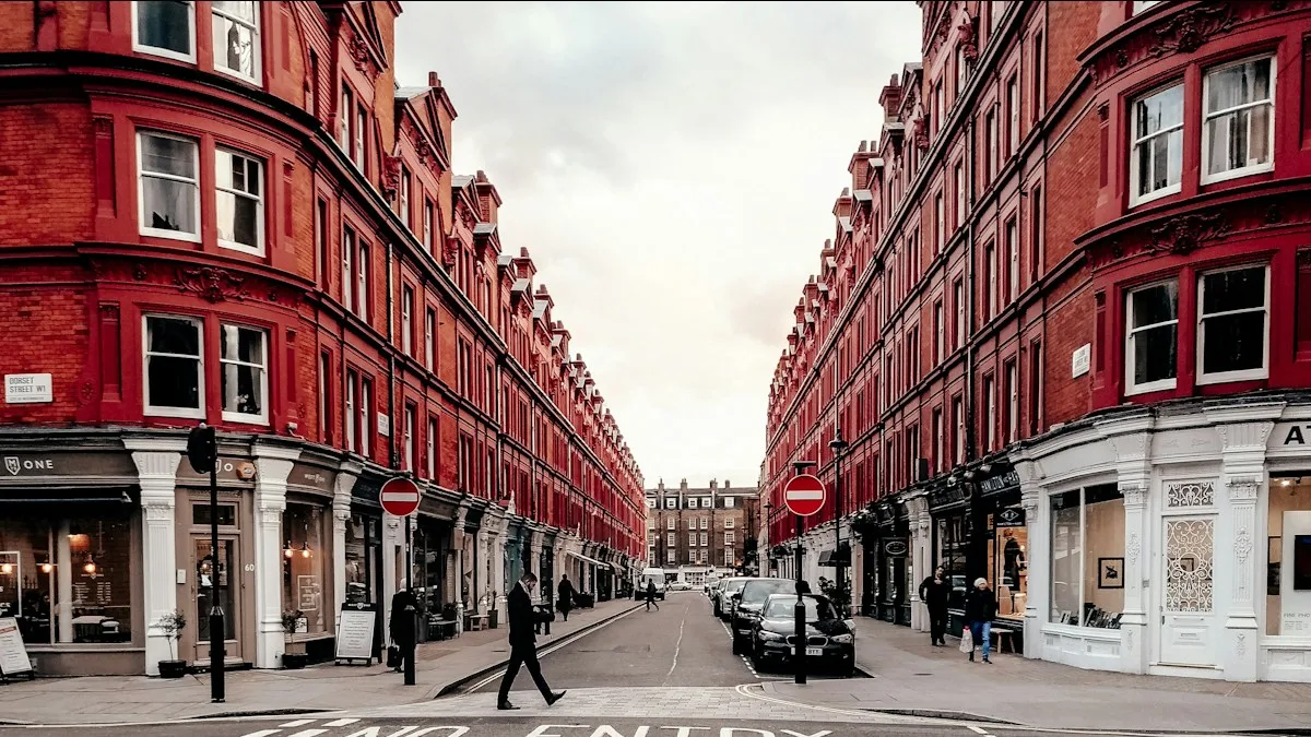 People walking on a London street between red brick buildings